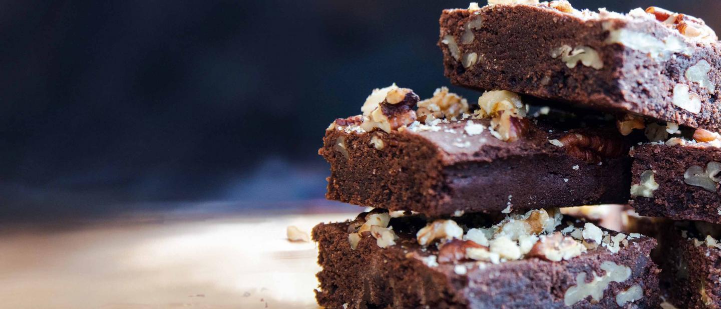 Una pila de brownies de chocolate y nuez, rociados con migas de nuez y nuez triturada, recién sacados del horno